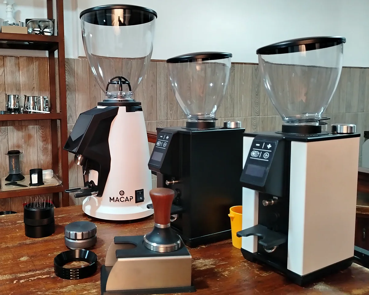 Molinos Macap con tamper, distribuidor y utensilios de barista en la barra